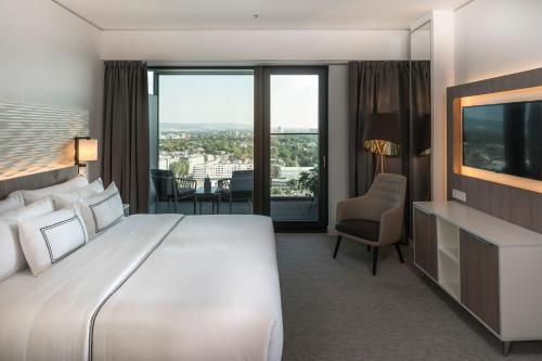 a hotel room with a large bed and a television at Meliá Frankfurt City in Frankfurt