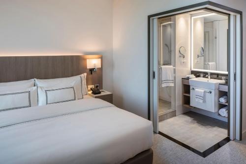 a bedroom with a large bed and a bathroom at Meliá Frankfurt City in Frankfurt