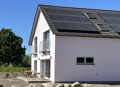 a white house with solar panels on the roof at B&B Zirbenduft in Ribnitz-Damgarten