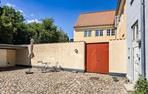 a patio with a red door and a umbrella and a building at 3 Bedroom Pet Friendly Apartment In Faaborg in Faaborg
