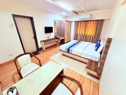 a hotel room with a bed and a desk at Hotel Praveen International in Ulhāsnagar