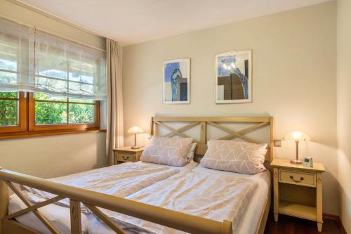 a bedroom with a bed with two night stands and two windows at Haus am Wald in Münstertal