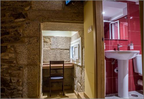 a bathroom with a sink and a counter with a chair at Oxford Suites Santiago de Compostela in Santiago de Compostela