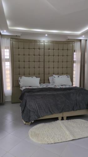 a bedroom with a large bed with a large headboard at Hidden Gem KAG Kitengela in Stony Athi