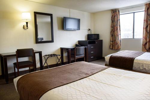 a hotel room with two beds and a desk and a mirror at Americas Best Value Inn New Paltz in New Paltz