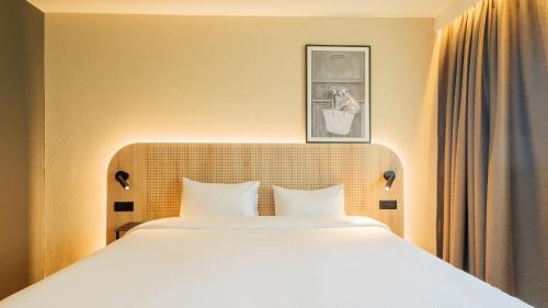 ein Schlafzimmer mit einem großen weißen Bett und einem Bild an der Wand in der Unterkunft TULIP Hotels & Residences - Marne-la-Vallee Torcy in Torcy