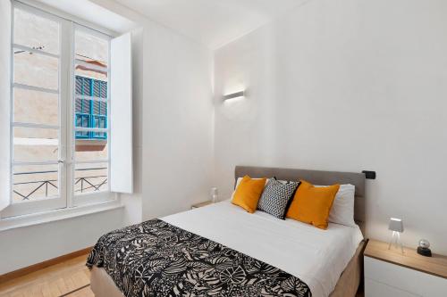a bedroom with a bed with orange pillows and a window at Aura Suites in Albenga