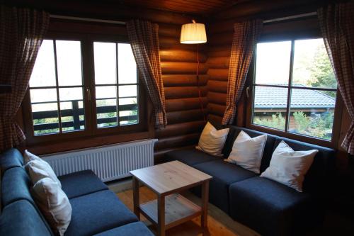 a living room with a blue couch and two windows at Chalet Grand Wastl in Wörgl