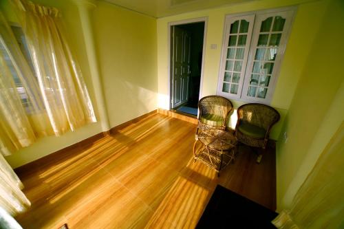 a living room with two chairs and a wooden floor at Holiday Heaven Munnar in Chinnakanal