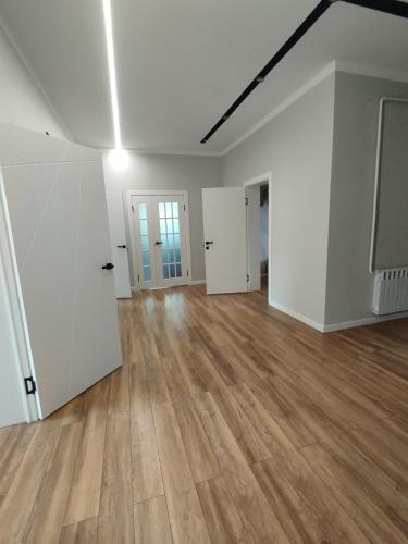 an empty living room with a television and wooden floors at Aziz House in Naryn