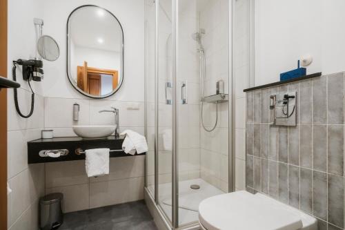 a bathroom with a shower and a sink and a mirror at Hotel Das Lola in Essen