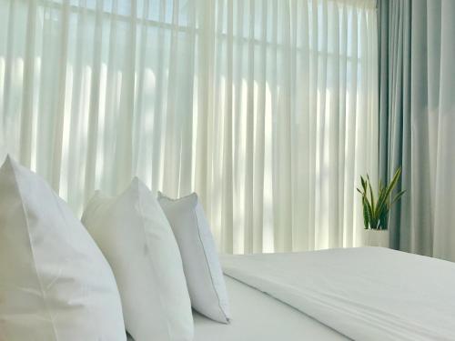 a white bed with white pillows in front of a window at TS Beach House in Phu Quoc