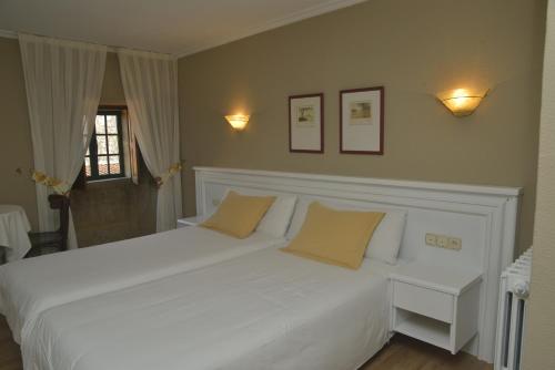 a bedroom with a white bed with two yellow pillows at Hotel Gastronómico Casa Rosalia in Brion