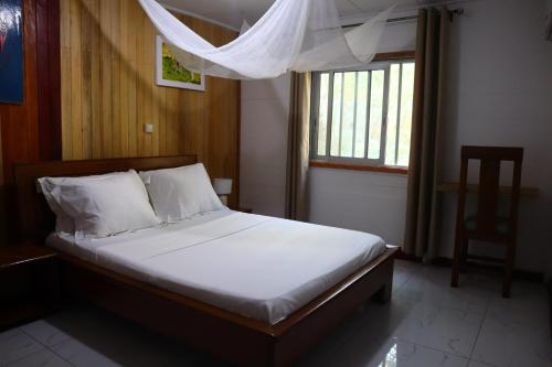 a bed in a bedroom with a window and a chair at Executive Suites & Apartments - VIP Services in Kribi