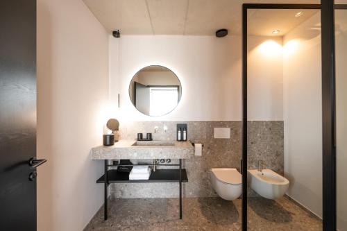 a bathroom with a sink and a toilet and a mirror at View - AgriSuites in Caldaro