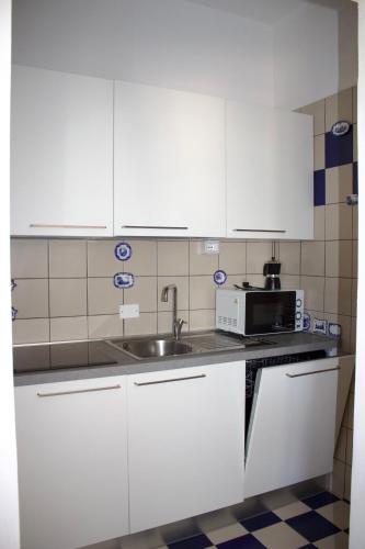 a kitchen with white cabinets and a sink and a microwave at CASA MAJOR Appartamenti in Cervia