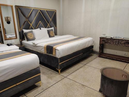 a hotel room with two beds and a table at Swiss Pearl Hotel Lahore in Lahore