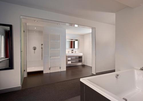 a bathroom with a mirror and a tub and a sink at Van der Valk Hotel Nuland - 's-Hertogenbosch in Nuland