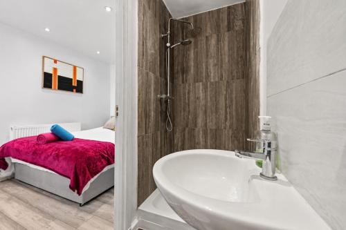 a bathroom with a sink and a tub and a bed at K Suites - Nuxley Road in Bexley