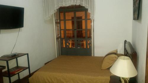 1 dormitorio con 1 cama con lámpara y ventana en Hostal Chordeleg, en Cuenca