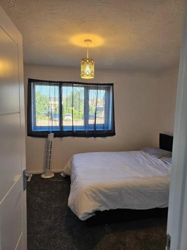 a bedroom with a bed and a window and a chandelier at The Chilux stylish apartment in Rainham