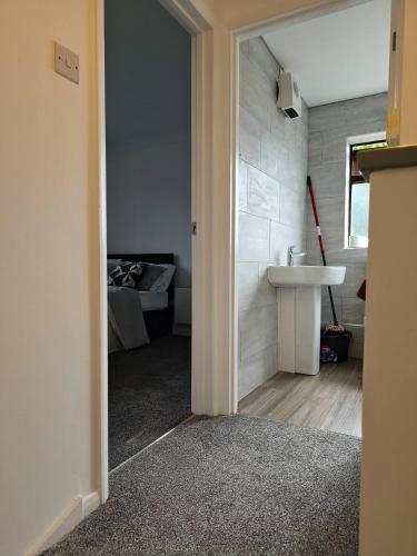 a bathroom with a sink and a bedroom with a bed at The Chilux stylish apartment in Rainham