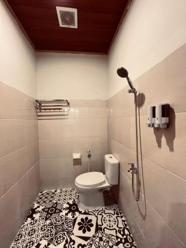 a bathroom with a toilet and a black and white tile floor at WLA Homestay in Labuan Bajo