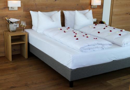 ein Bett mit weißer Bettwäsche und roten Herzen darauf in der Unterkunft Buchners Hotel & Restaurant in Niederwinkling