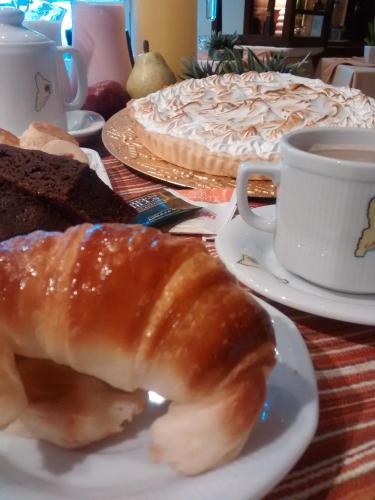 a table with a plate of bread and a cake and a cup of coffee at Hotel Costa Limay in Plottier