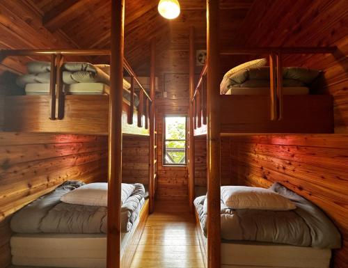 two bunk beds in a cabin with wooden walls at Maruta なんもく村 in Minamimaki