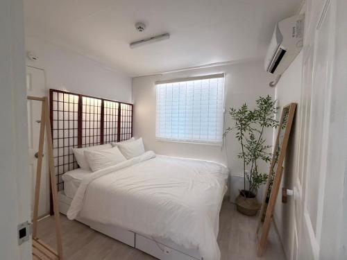 a bedroom with a bed with white sheets and a window at 헤이데이서울 in Seoul