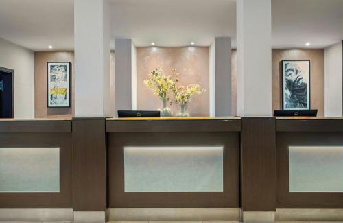 a lobby with a counter with flowers in a vase at Leonardo Hotel München City Center in Munich
