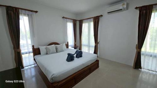 a bedroom with a bed with white sheets and windows at Chaya village F shared pool jacuzzi in Phra Ae beach