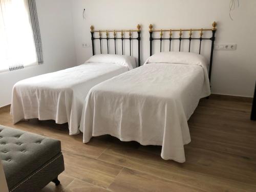 two beds with white blankets on them in a room at El Balcón de La Vega in Vinuesa