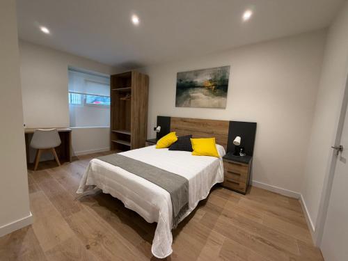a bedroom with a bed with yellow pillows and a desk at MTM Rooms in Santander