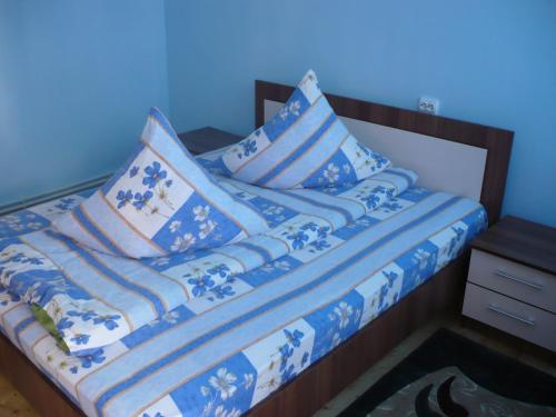 a bed with blue and white blankets and pillows at Pensiunea Daiana in Albac