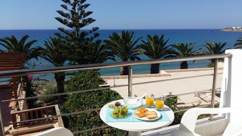 a table with a plate of food on a balcony with the ocean at Blue Ocean Apartments in Makry Gialos