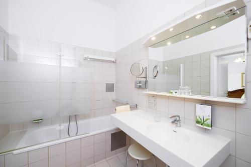 ein weißes Badezimmer mit Waschbecken und Spiegel in der Unterkunft Hotel Austria - Wien in Wien