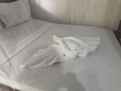 a white stuffed animal laying on a white bed at Nanakizilodge in Mtendeni