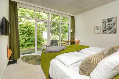 a bedroom with a bed with a green blanket on it at Vilcon Hotel & Konferencegaard in Slagelse