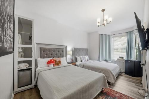 a white bedroom with two beds and a television at Serenity Inn in Niagara Falls