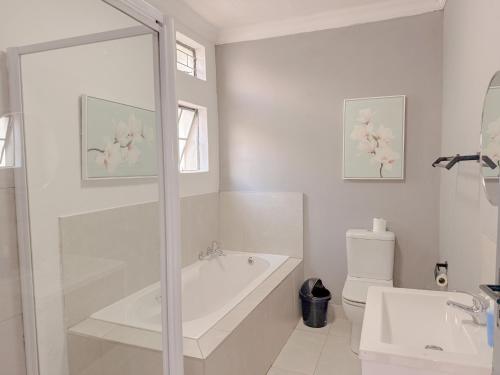 a white bathroom with a tub and a toilet at Amoris on Anderson in Pretoria