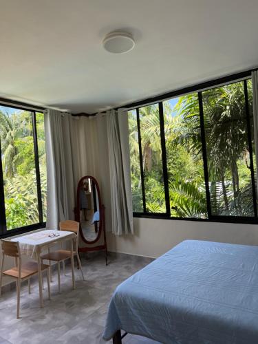 ein Schlafzimmer mit einem Bett, einem Tisch und einigen Fenstern in der Unterkunft Phines Place in Panglao