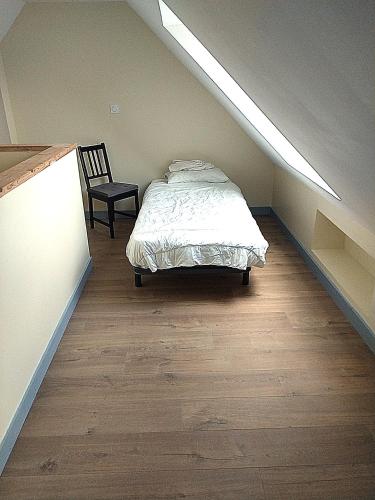 a bedroom with a bed and a chair in a attic at Ker Louwen chambre d' hôte in Corseul
