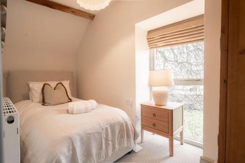 a bedroom with a bed and a window at Critchlow Cottage in Buxton