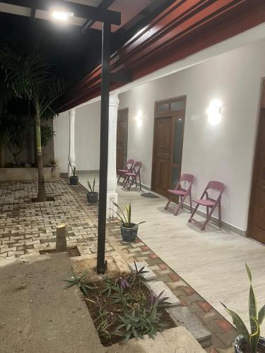 a patio with red chairs and a building at Yala Villa Harmony in Debarawewa