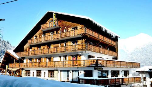 duży budynek z drewnianymi balkonami w śniegu w obiekcie Hotel Le Concorde w mieście Morzine