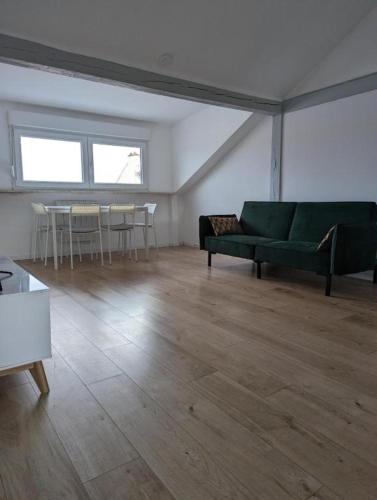 a living room with a green couch and a table at Le Vauban - appartement 2 chambres, salon, cuisine équipée, parking et wifi gratuit in Mulhouse