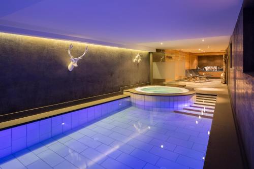 a swimming pool with a tub in a room at Hotel Somont in Selva di Val Gardena