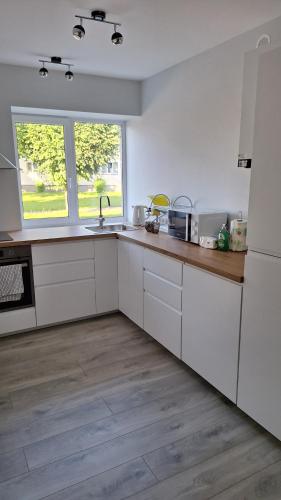 a kitchen with white cabinets and a wooden floor at Petite Haven in Grobiņa